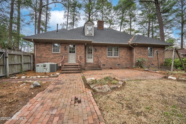 back of house featuring crawl space, entry steps, a chimney, and brick siding