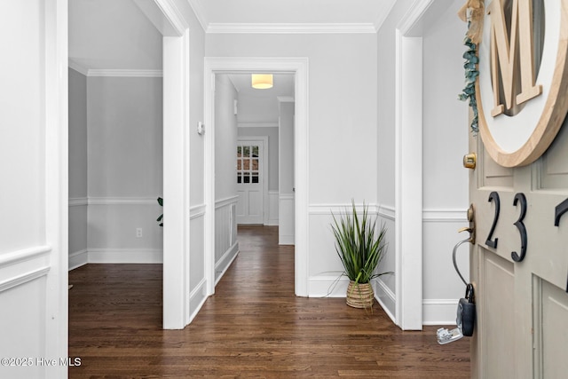 hallway with a decorative wall, wainscoting, crown molding, and wood finished floors