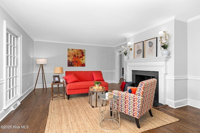 living area with ornamental molding, wood finished floors, and a fireplace with raised hearth