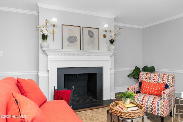 living room featuring wood finished floors, baseboards, a fireplace with flush hearth, and ornamental molding