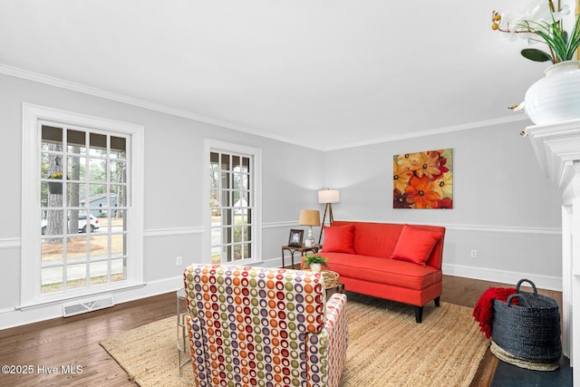 living room with visible vents, baseboards, wood finished floors, and crown molding