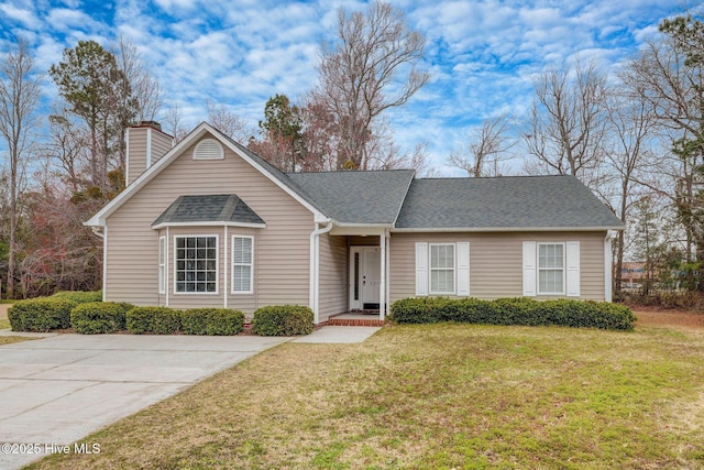 ranch-style home featuring roof with shingles, a chimney, and a front yard