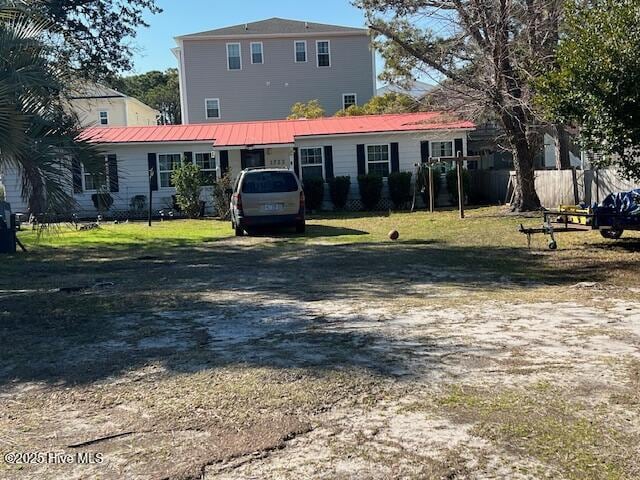 rear view of house featuring a yard and metal roof