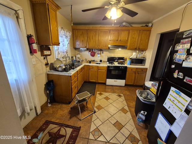 kitchen with range hood, gas stove, freestanding refrigerator, stainless steel microwave, and tasteful backsplash