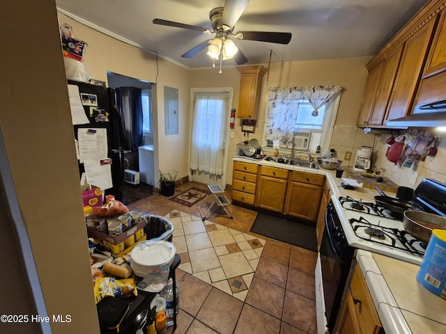 kitchen featuring backsplash, light countertops, electric panel, range with gas stovetop, and brown cabinetry