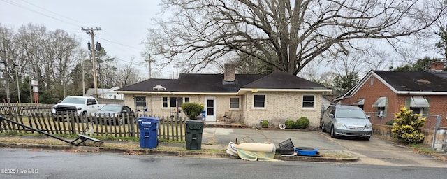 view of front of property featuring brick siding, a fenced front yard, and a chimney