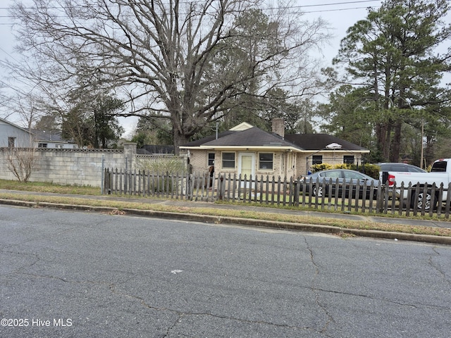 bungalow-style house with a fenced front yard and a chimney