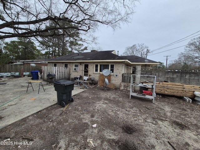 back of house with fence, a chimney, brick siding, and a patio area