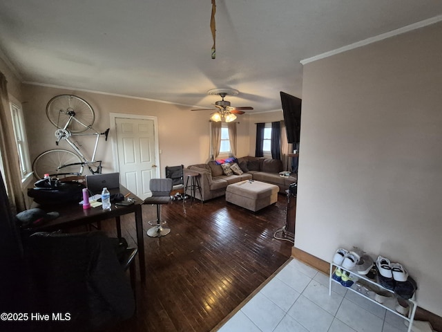 living area featuring hardwood / wood-style floors, crown molding, baseboards, and ceiling fan