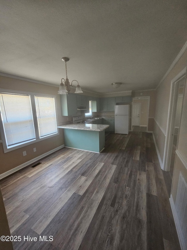 kitchen with dark wood finished floors, white appliances, crown molding, and a peninsula