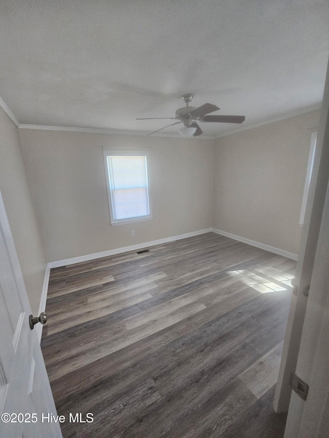 unfurnished room with visible vents, ornamental molding, a ceiling fan, wood finished floors, and baseboards