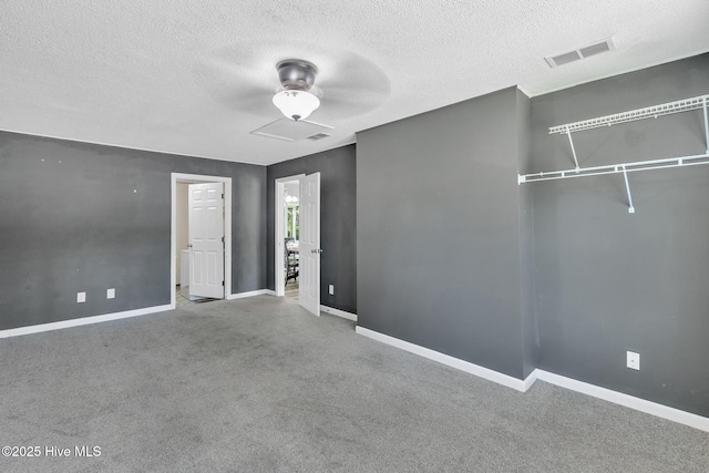 unfurnished bedroom with baseboards, carpet, a textured ceiling, and visible vents