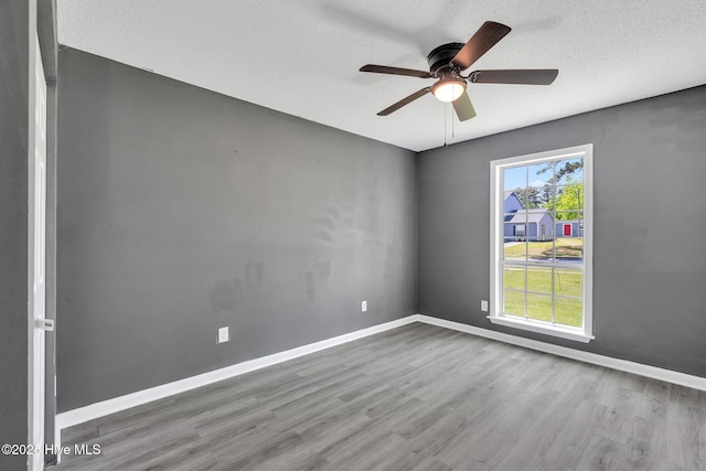 empty room featuring baseboards, ceiling fan, a textured ceiling, and wood finished floors