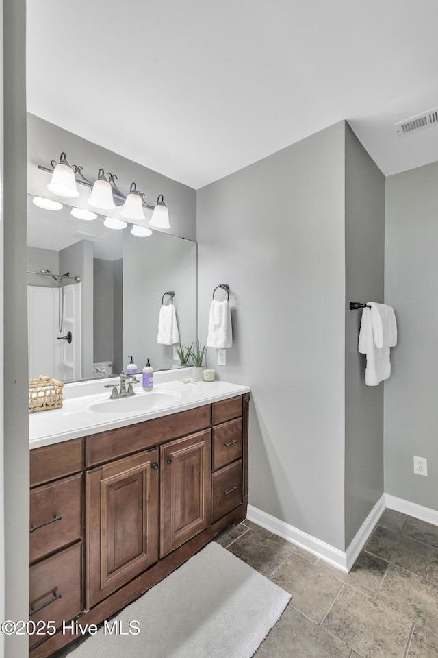 bathroom featuring baseboards, visible vents, stone finish floor, and vanity