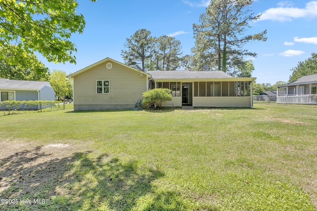 rear view of property with a sunroom, a lawn, fence, and a chimney