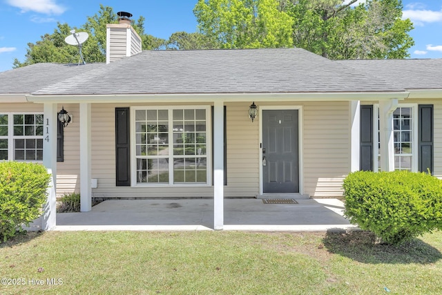 property entrance with roof with shingles, covered porch, and a chimney