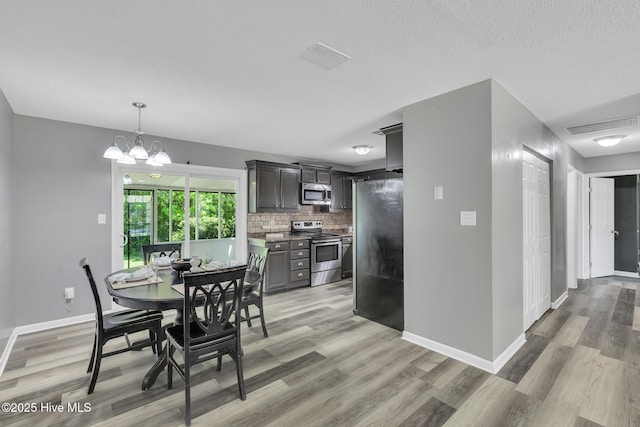 dining area with baseboards, a notable chandelier, light wood-style flooring, and visible vents
