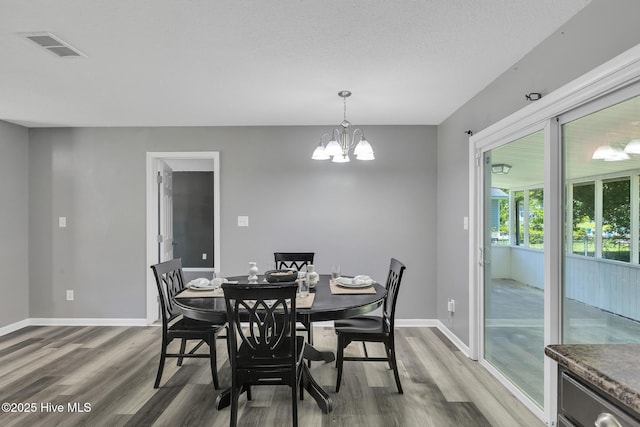 dining space with baseboards, a notable chandelier, wood finished floors, and visible vents