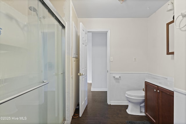 full bathroom featuring vanity, a shower stall, toilet, and wood finished floors