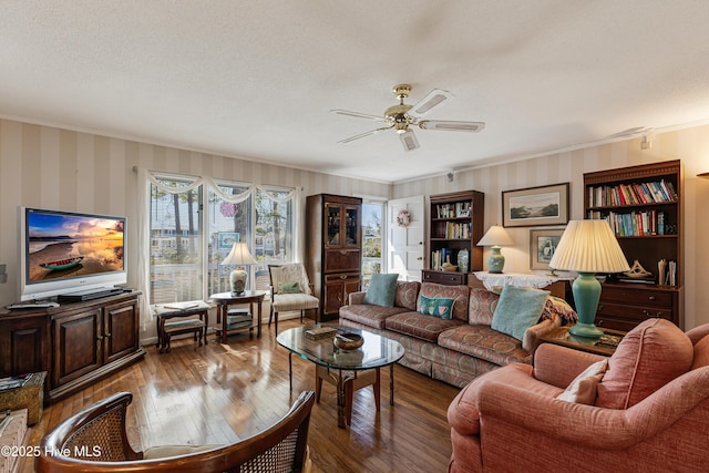 living area with wood-type flooring, a textured ceiling, ornamental molding, and a ceiling fan