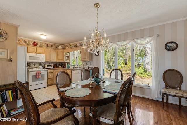 dining room with a wealth of natural light, wallpapered walls, a textured ceiling, and light wood-style floors