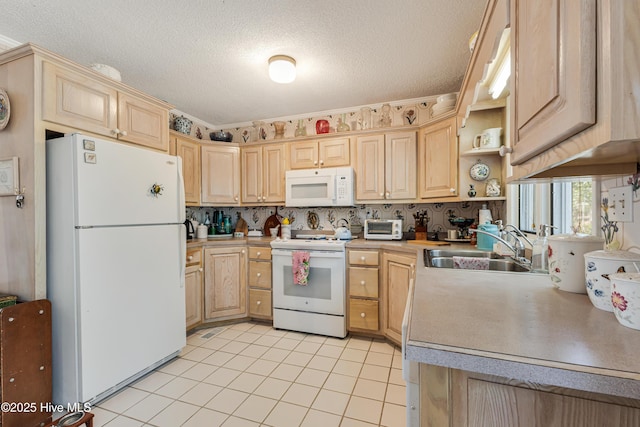 kitchen with a sink, white appliances, and light brown cabinetry