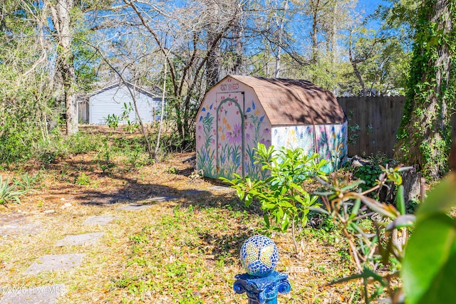 view of yard featuring an outbuilding, a storage shed, and fence