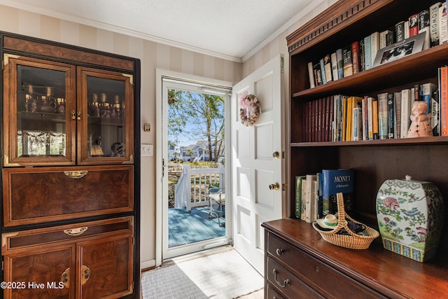 doorway with a textured ceiling and ornamental molding