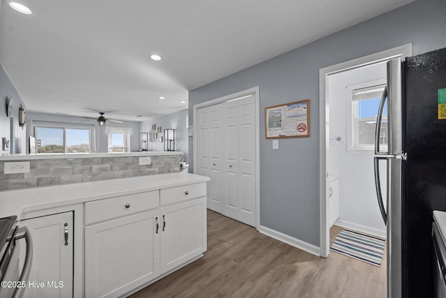 kitchen featuring white cabinetry, a wealth of natural light, light wood finished floors, and freestanding refrigerator