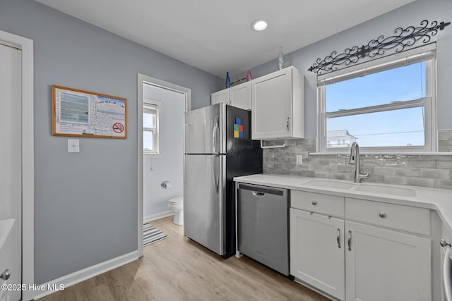 kitchen featuring a sink, white cabinets, a healthy amount of sunlight, and stainless steel appliances