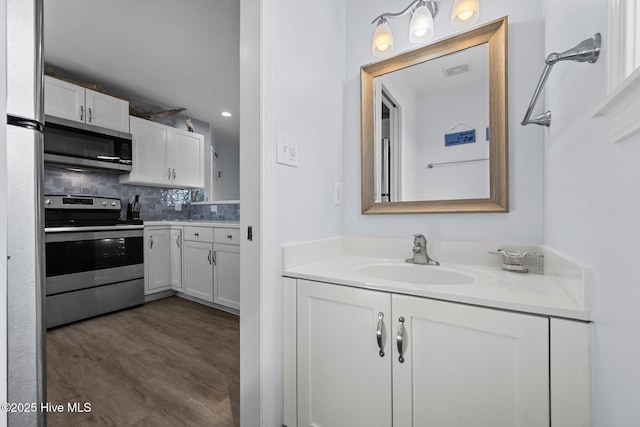 bathroom featuring decorative backsplash, vanity, visible vents, and wood finished floors