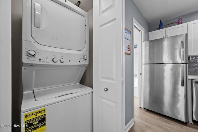 washroom featuring light wood finished floors, laundry area, and stacked washer and dryer