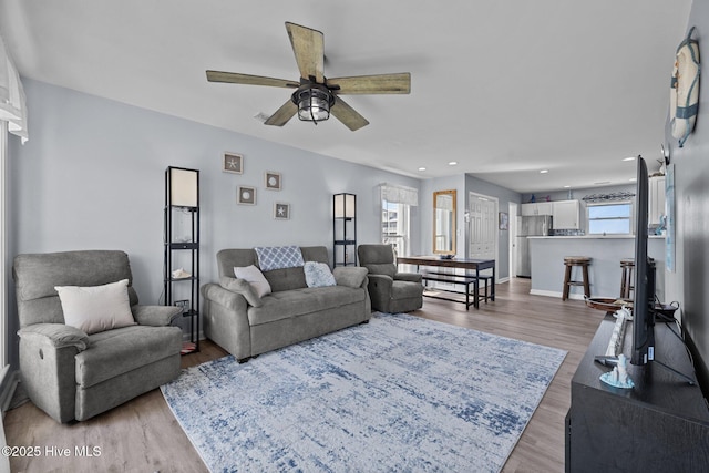 living area featuring a wealth of natural light, baseboards, a ceiling fan, and wood finished floors