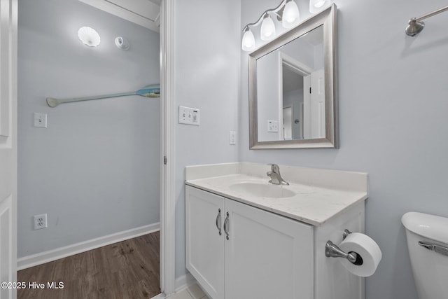 bathroom featuring toilet, vanity, baseboards, and wood finished floors