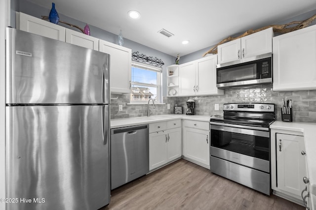 kitchen with a sink, white cabinets, light wood-style flooring, and stainless steel appliances