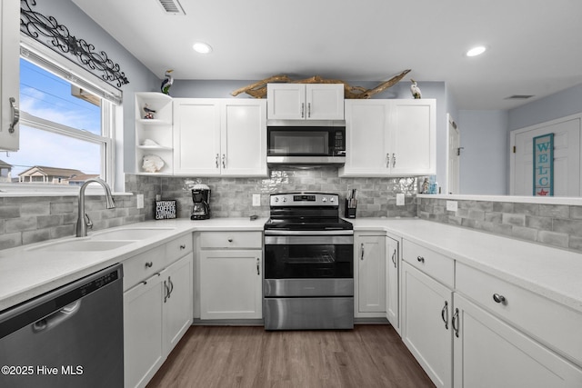 kitchen featuring tasteful backsplash, white cabinetry, stainless steel appliances, and a sink