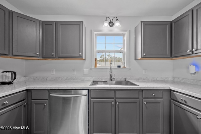 kitchen with a sink, gray cabinetry, light countertops, and stainless steel dishwasher