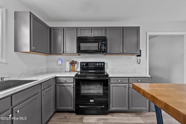 kitchen featuring black appliances, light wood-style floors, gray cabinets, and butcher block countertops