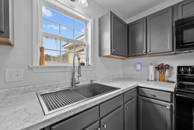 kitchen with a sink, black appliances, gray cabinets, and light countertops