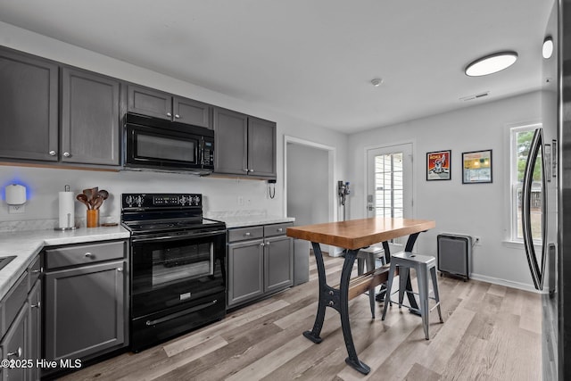 kitchen with visible vents, light wood-type flooring, light countertops, gray cabinets, and black appliances