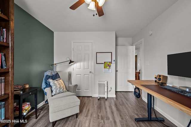 office space with radiator, wood finished floors, baseboards, and ceiling fan