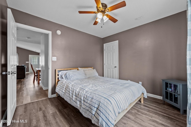 bedroom with a ceiling fan, lofted ceiling, baseboards, and wood finished floors