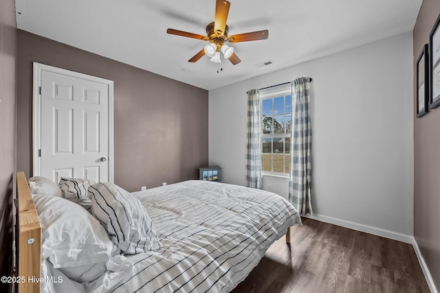 bedroom featuring visible vents, a ceiling fan, baseboards, and wood finished floors