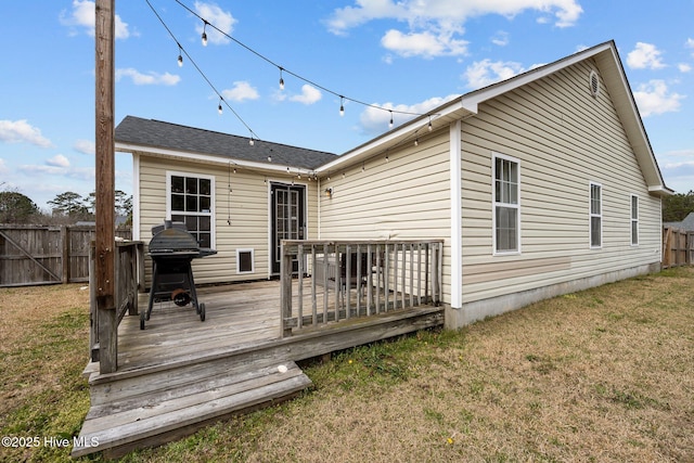 rear view of house with a deck, fence, and a lawn