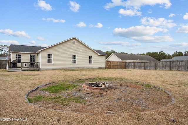 rear view of house with a wooden deck, an outdoor fire pit, and fence