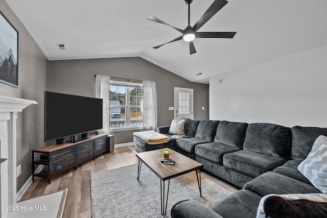 living area with light wood-type flooring, visible vents, a ceiling fan, baseboards, and vaulted ceiling