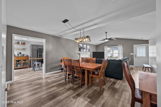 dining area featuring baseboards, lofted ceiling, light wood-style floors, and a ceiling fan