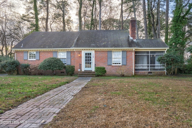 view of front of house featuring a front lawn, entry steps, crawl space, brick siding, and a chimney