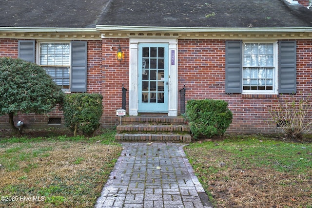 entrance to property with crawl space, brick siding, and roof with shingles