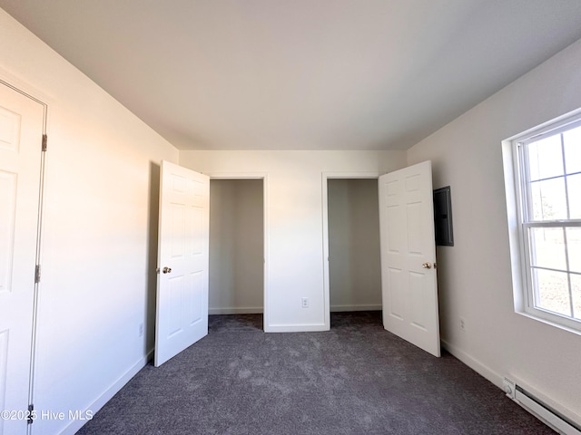 unfurnished bedroom featuring dark colored carpet, baseboards, and baseboard heating